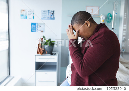 Sad african american female patient sitting on bed and crying in patient room at hospita, copy space Sad african american female patient sitting on bed and crying in patient room at hospita, copy space 105522940