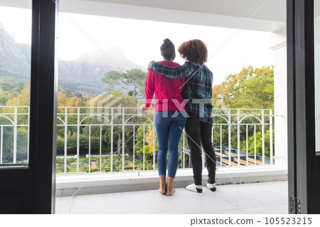 Rear view of happy diverse couple on balcony embracing and admiring view at home, copy space Rear view of happy diverse couple on balcony embracing and admiring view at home, copy space 105523215