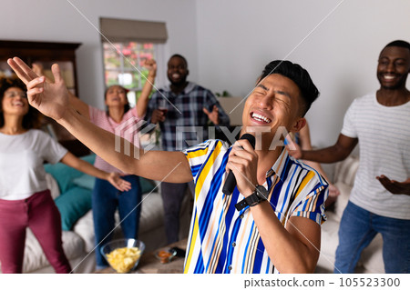 Happy diverse friends dancing and karaoke singing with microphone at home Happy diverse friends dancing and karaoke singing with microphone at home 105523300