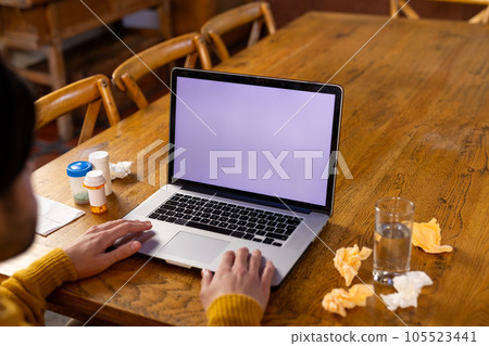 Indian man with medication on table making video call using laptop, copy space on screen at home 105523441