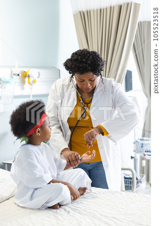 African american female doctor examining girl patient using stethoscope at hospital African american female doctor examining girl patient using stethoscope at hospital 105523518