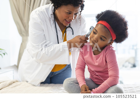 African american female doctor examining girl patient using otoscopy at hospital African american female doctor examining girl patient using otoscopy at hospital 105523521