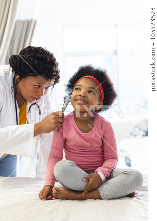 African american female doctor examining girl patient using otoscopy at hospital African american female doctor examining girl patient using otoscopy at hospital 105523523
