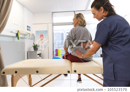 Caucasian female physiotherapist and senior woman massaging back at hospital 105523570