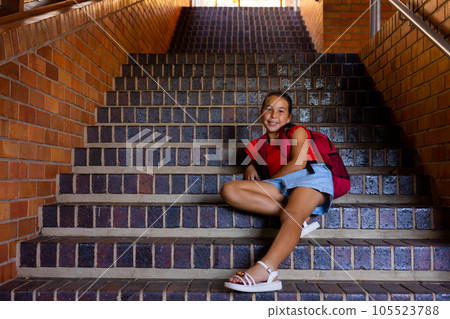 Portrait of happy caucasian schoolgirl sitting on stairs at school, copy space Portrait of happy caucasian schoolgirl sitting on stairs at school, copy space 105523788