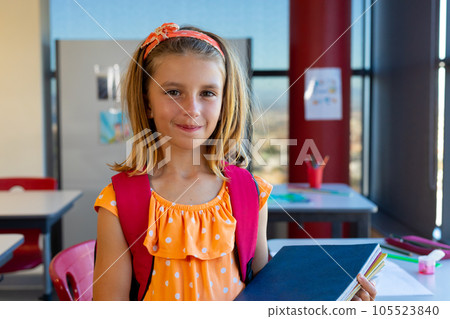 Portrait of happy caucasian schoolgirl with school bag and books in classroom at elementary school 105523840