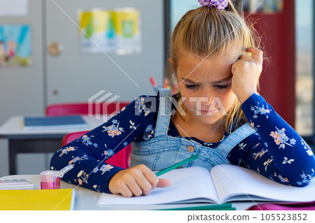 Exhausted caucasian schoolgirl sitting at desk and learning in classroom at elementary school Exhausted caucasian schoolgirl sitting at desk and learning in classroom at elementary school 105523852