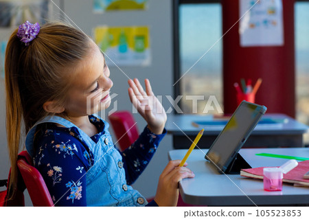Caucasian girl waving while having videocall on digital tablet with copy space at elementary school Caucasian girl waving while having videocall on digital tablet with copy space at elementary school 105523853