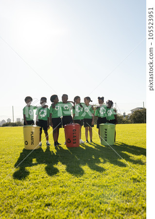 Happy diverse children collecting recycling embracing in sunny elementary school field, copy space 105523951