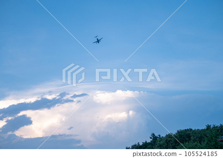 A silhouette of an airplane flying in the blue sky 105524185