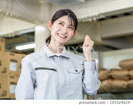 Young female staff standing with fist pump in warehouse of distribution center 105524829