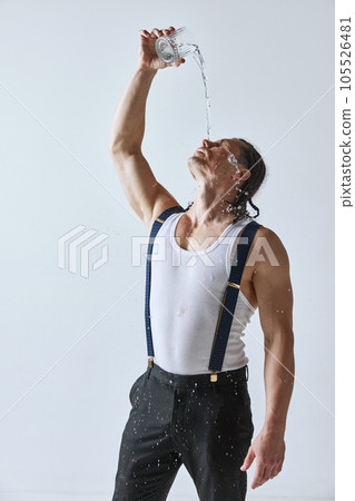 Portrait of handsome mature man with muscular body pouring water on face against grey studio background 105526481