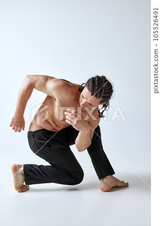 Athletic man posing in motion shirtless, in pants against grey studio background. Healthy, strong, relief body 105526491