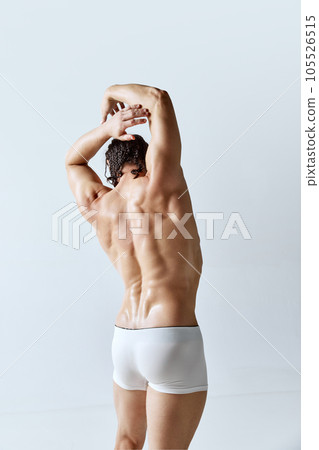 Rear view image of man posing shirtless in underwear against grey studio background. Relief back, muscular, healthy body Rear view image of man posing shirtless in underwear against grey studio background. Relief back, muscular, healthy body 105526515