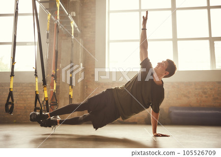 Making perfect body. Young athletic man exercising with suspension straps at gym Making perfect body. Young athletic man exercising with suspension straps at gym 105526709