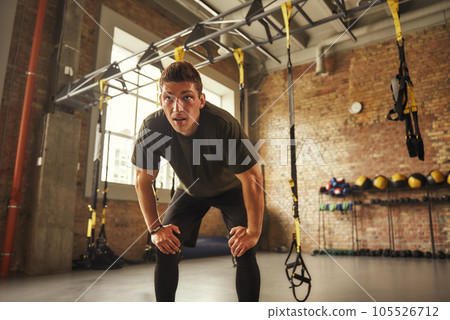 Time to rest. Young athletic man in sportswear looking exhausted after workout while standing at loft style gym 105526712