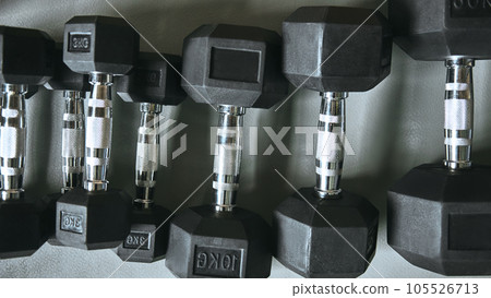 Close up of many metal black dumbbells on the floor at gym. Weight training equipment 105526713