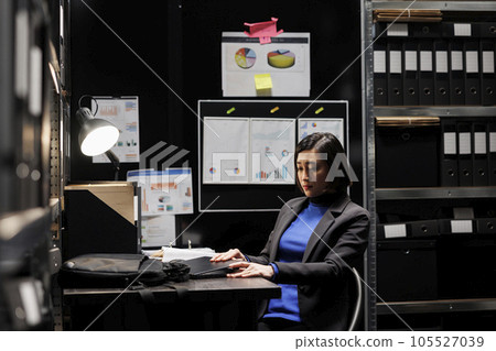 Accountant businesswoman employee unpacking laptop in office suitcase bag starting shiftwork. Bookkeeping executive in archival depository filled with cabinet, folders and flowcharts Accountant businesswoman employee unpacking laptop in office suitcase bag starting shiftwork. Bookkeeping executive in archival depository filled with cabinet, folders and flowcharts 105527039