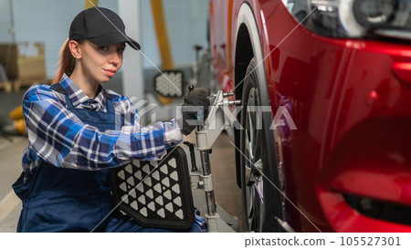 A female auto mechanic makes a camber. Woman working in a car service. 105527301