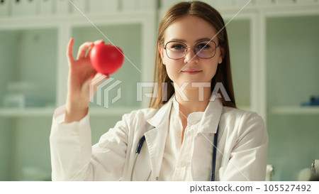 Happy female cardiologist doctor holding heart figure in hand Happy female cardiologist doctor holding heart figure in hand 105527492