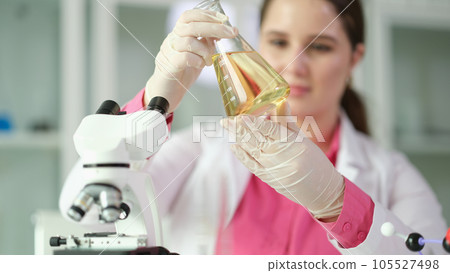 Researcher scientist student holding flask with yellow liquid Researcher scientist student holding flask with yellow liquid 105527498