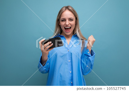 successful charming blonde girl rejoices and shouts while holding a smartphone in her hands on an successful charming blonde girl rejoices and shouts while holding a smartphone in her hands on an 105527745