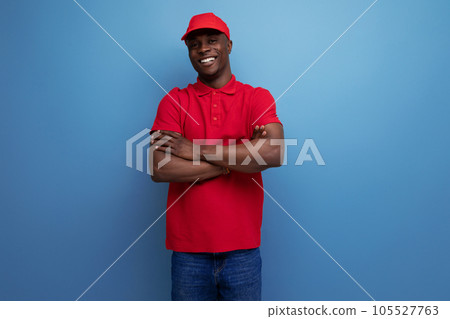 handsome young courier american man wearing corporate clothing consisting of a red cap and t-shirt 105527763