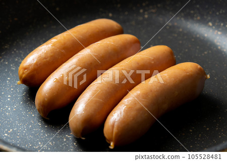 A cooking scene in which the wiener sausage is cut in and baked in a frying pan. 105528481