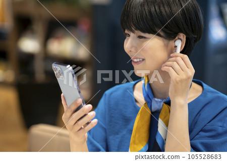 A young woman wearing earphones and holding a smartphone Photography cooperation: Credisce (Maruzen Yushodo Co., Ltd.) A young woman wearing earphones and holding a smartphone Photography cooperation: Credisce (Maruzen Yushodo Co., Ltd.) 105528683