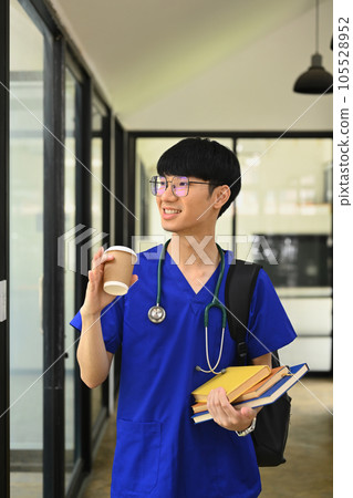 Portrait of medical student man wearing blue scrubs with stethoscope standing near window at campus Portrait of medical student man wearing blue scrubs with stethoscope standing near window at campus 105528952