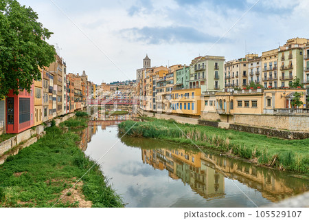 Colorful yellow and orange houses and bridge Pont de Sant Agusti reflected in water river Onyar, in Girona, Catalonia, Spain. Church of Sant Feliu and Saint Mary Cathedral at background. BRIDGE in the Colorful yellow and orange houses and bridge Pont de Sant Agusti reflected in water river Onyar, in Girona, Catalonia, Spain. Church of Sant Feliu and Saint Mary Cathedral at background. BRIDGE in the 105529107