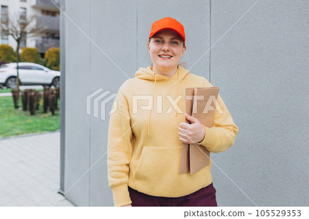 Happy Delivery woman with parcel in hand sending parcel to customer front of the house from shopping online with good service. Courier send a package to destination. 105529353