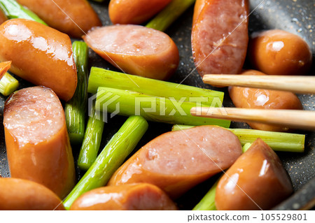 煎鍋裡煎香腸和蒜苗的烹飪場景。 105529801