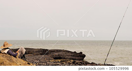 A Relaxed Fisherman Awaits His Catch Against a Beautiful Coastal Backdrop 105529996