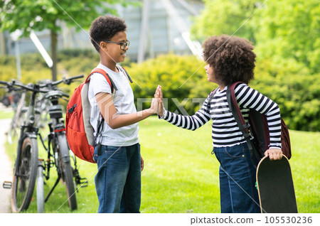 Two schoolkids with skateboard in green sunny park having fun together enjoying summer time. Two schoolkids with skateboard in green sunny park having fun together enjoying summer time. 105530236