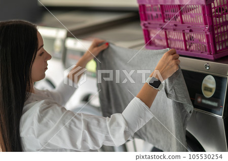 Young woman doing his weekly washing in a laundromat. Young woman doing his weekly washing in a laundromat. 105530254