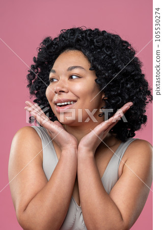 Smiling curly-haired brunette woman on pink background 105530274