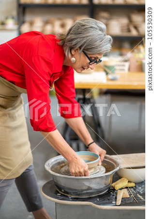 Woman potter taking finished plate from pottery wheel, making earthenware. Woman potter taking finished plate from pottery wheel, making earthenware. 105530309