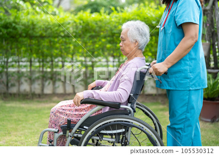Doctor help and care Asian senior woman patient sitting on wheelchair at park in nursing hospital ward, healthy strong medical concept. 105530312