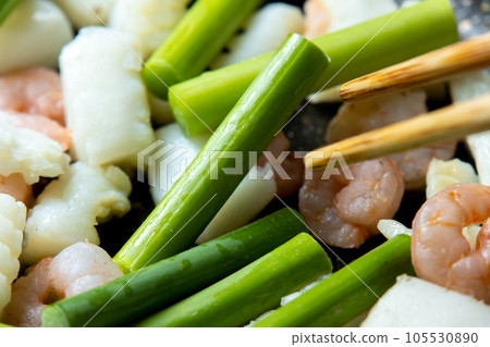海鮮(魷魚和蝦)和蒜苗在煎鍋中煎炸的烹飪場景。 海鮮(魷魚和蝦)和蒜苗在煎鍋中煎炸的烹飪場景。 105530890