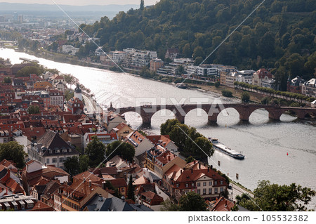 Aerial drone view over famous city of Heidelberg Germany with bridge on river Neckar. Dramatic cloudy sky with sunbeams over old town and mountains 105532382