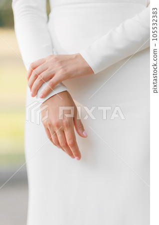 Unrecognisable woman in elegant white wedding slim dress outdoors. Cropped photo of woman hands with classic manicure. Fashionable stylish satin dress without ornaments. Wedding bridal gown details. Unrecognisable woman in elegant white wedding slim dress outdoors. Cropped photo of woman hands with classic manicure. Fashionable stylish satin dress without ornaments. Wedding bridal gown details. 105532383