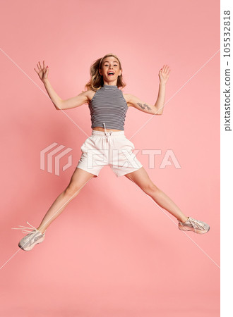 Full length photo of amazing young woman jumping high enjoy making star shape with hands and legs over pink color background. 105532818