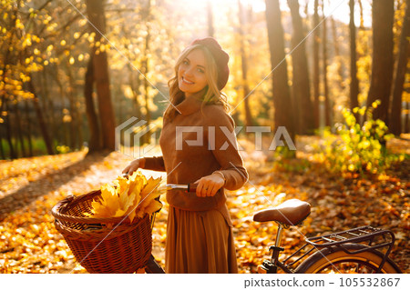 Stylish woman with a bicycle enjoying autumn weather in the park. Beautiful Woman in the autumn forest. 105532867