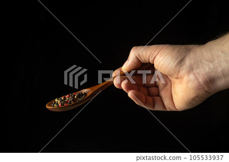 Dry pepper in a vintage spoon in the chef hand before adding to food. Black space for advertising Dry pepper in a vintage spoon in the chef hand before adding to food. Black space for advertising 105533937