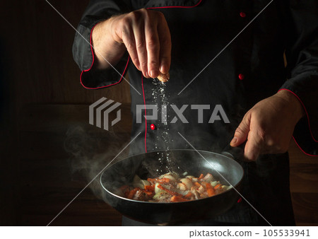 The cook adds salt to a steaming hot pan. Menu idea for a hotel with advertising space. Asian national cuisine. Restaurant menu or recipe. Copy space The cook adds salt to a steaming hot pan. Menu idea for a hotel with advertising space. Asian national cuisine. Restaurant menu or recipe. Copy space 105533941