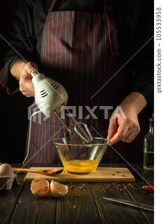 The chef uses a hand-held electric mixer to prepare a delicious egg breakfast or lunch. Menu idea for restaurant or hotel 105533958