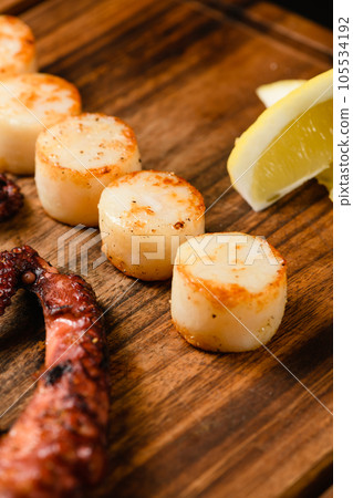 Assorted grilled seafood on wooden cutting board, dark background. Assorted grilled seafood on wooden cutting board, dark background. 105534192