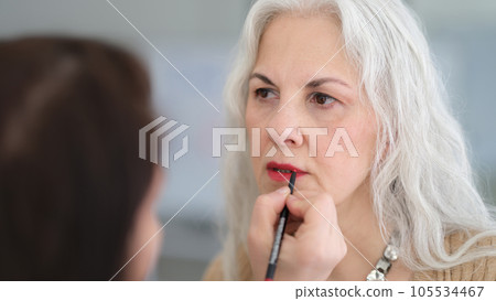 Woman at beautician appointment applies makeup 105534467