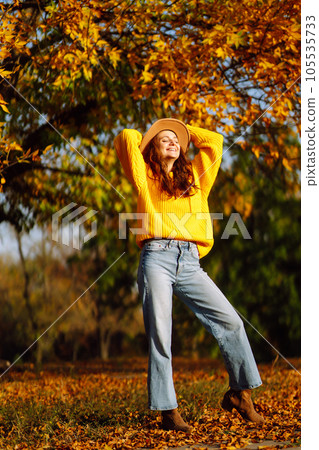 Young woman in a yellow sweater and jeans resting in nature. Fashion, style concept. People, lifestyle. Young woman in a yellow sweater and jeans resting in nature. Fashion, style concept. People, lifestyle. 105535733